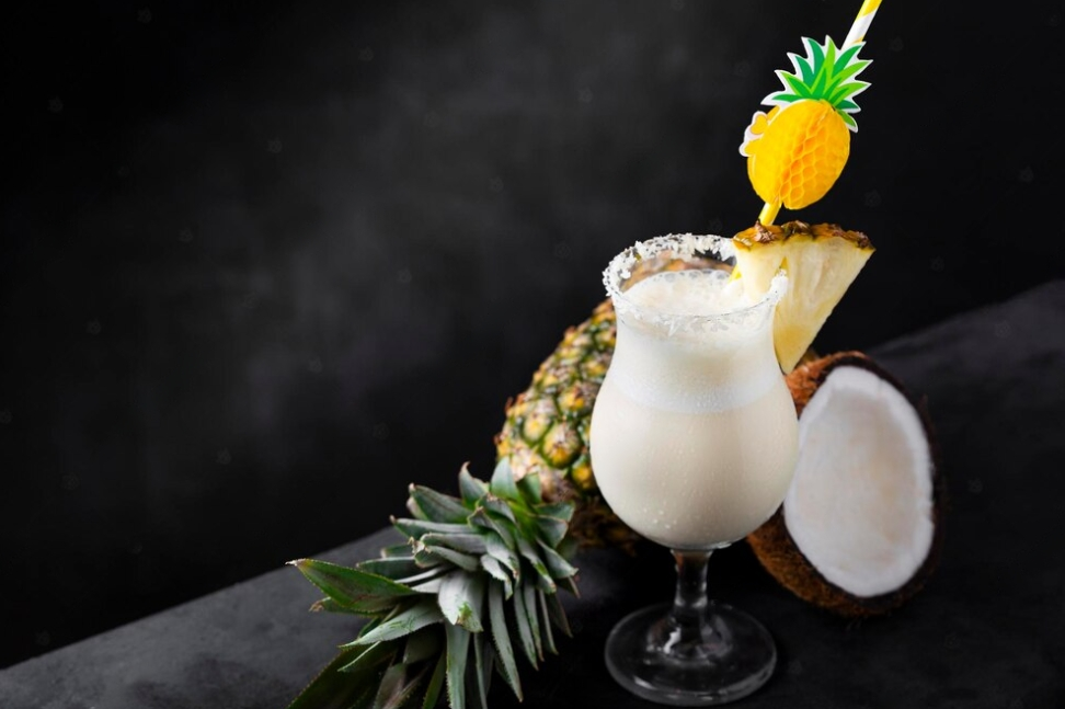 pina colada drink decorated with pineapple, pineapple, and coconut on the black table