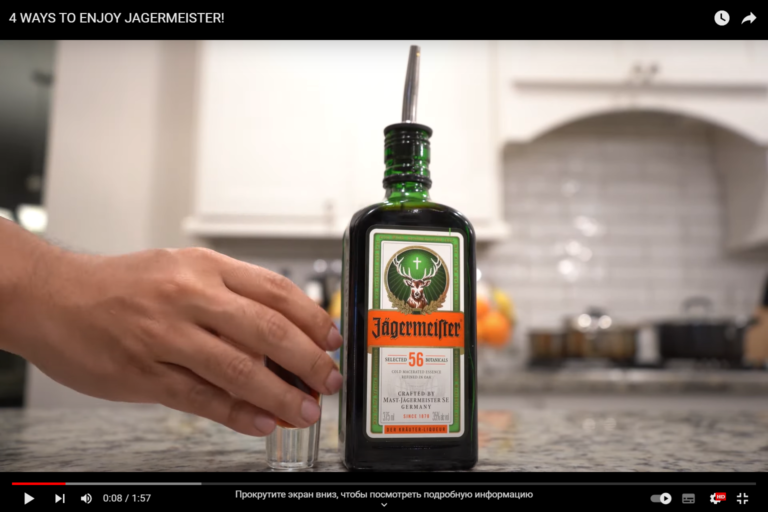 A hand takes a shot of a drink, next to it is a bottle of jager