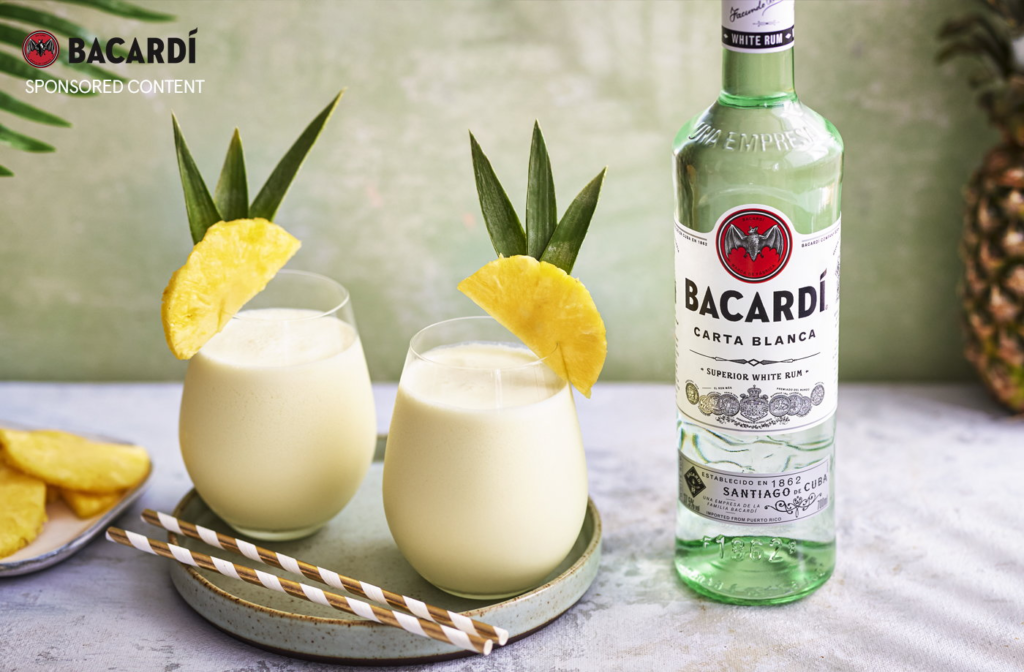 A bottle of bacardi and two cocktails with pineapple pieces