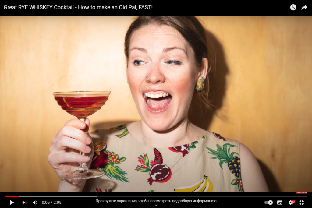 The girl holds a cocktail in her hand and laughs