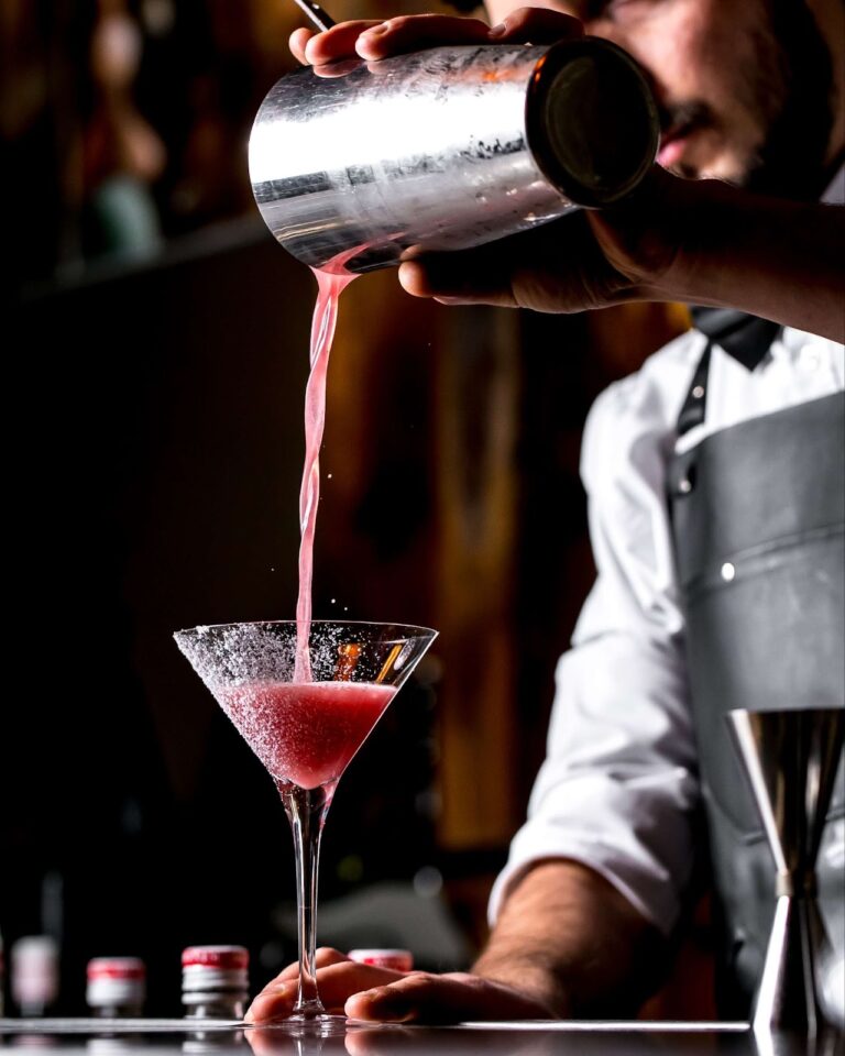 Bartender pours cocktail into martini glass