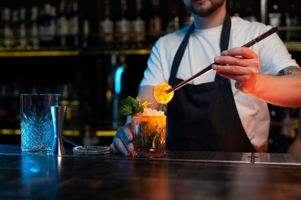 The bartender puts an orange in the cocktail