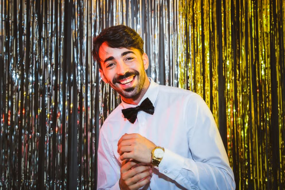 man in a white shirt with a watch standing near the shiny decorated wall